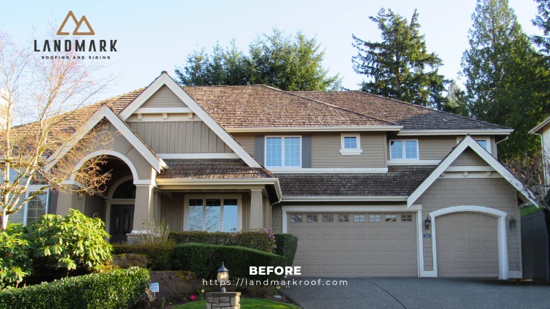 A large two story beige house with a wooden shingle roof, arched entryway, and a three car garage. The yard features trimmed bushes and trees. The image includes the Landmark Roofing and Siding logo and website info.