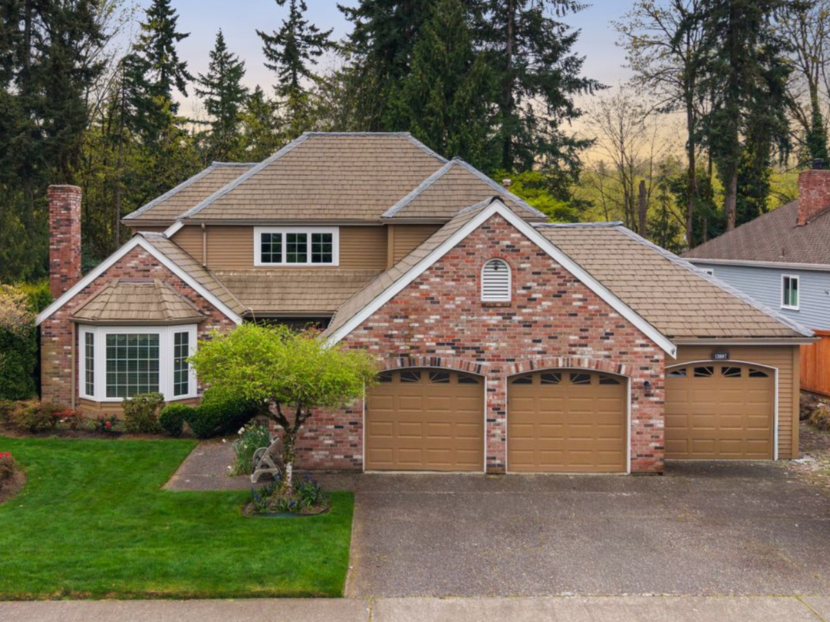Before roof replacement on a two-story brick home with an aging tan roof